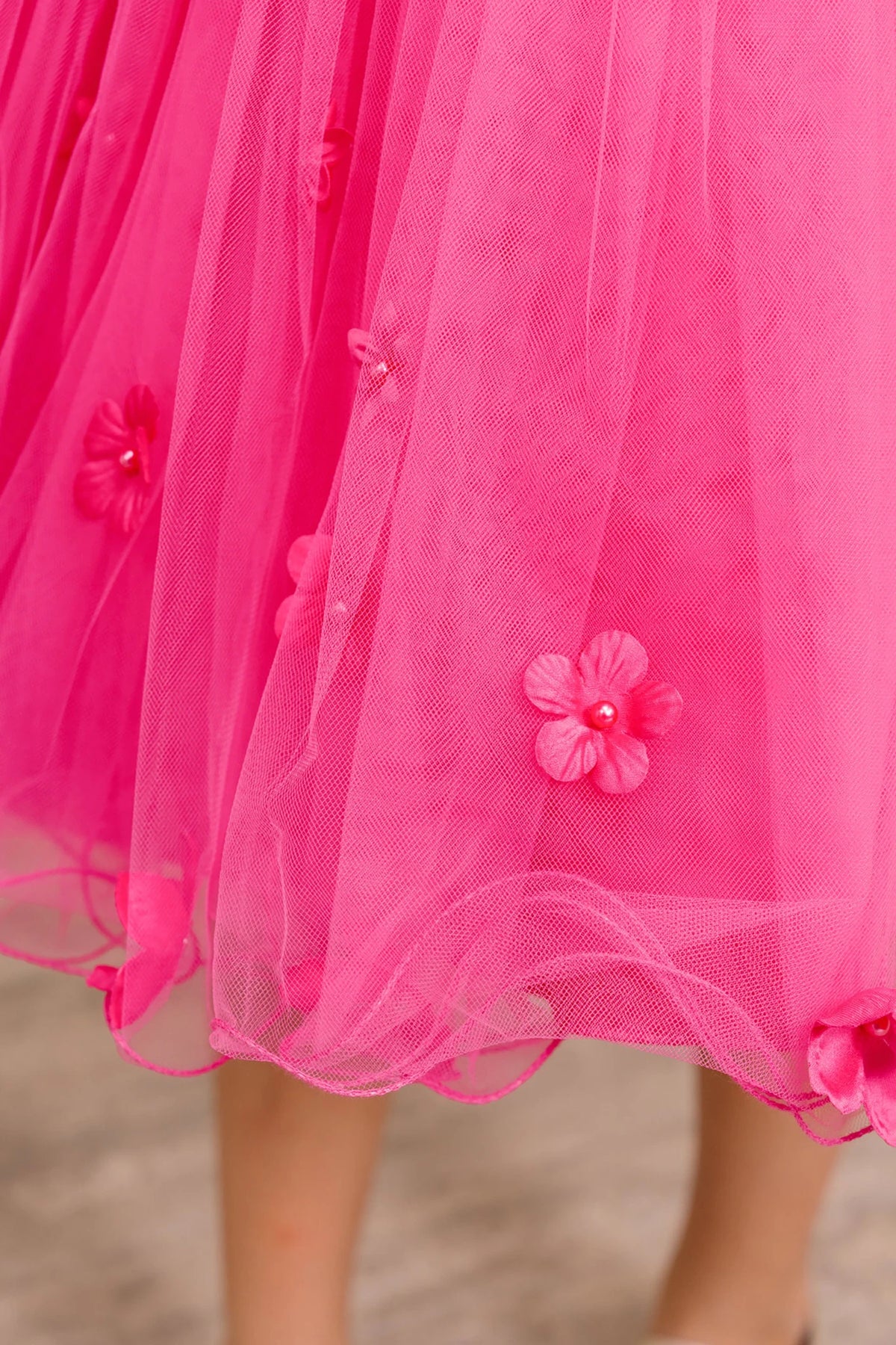 Close-up of a bright fuchsia tulle skirt with floral embellishments. Flower girl dress.
