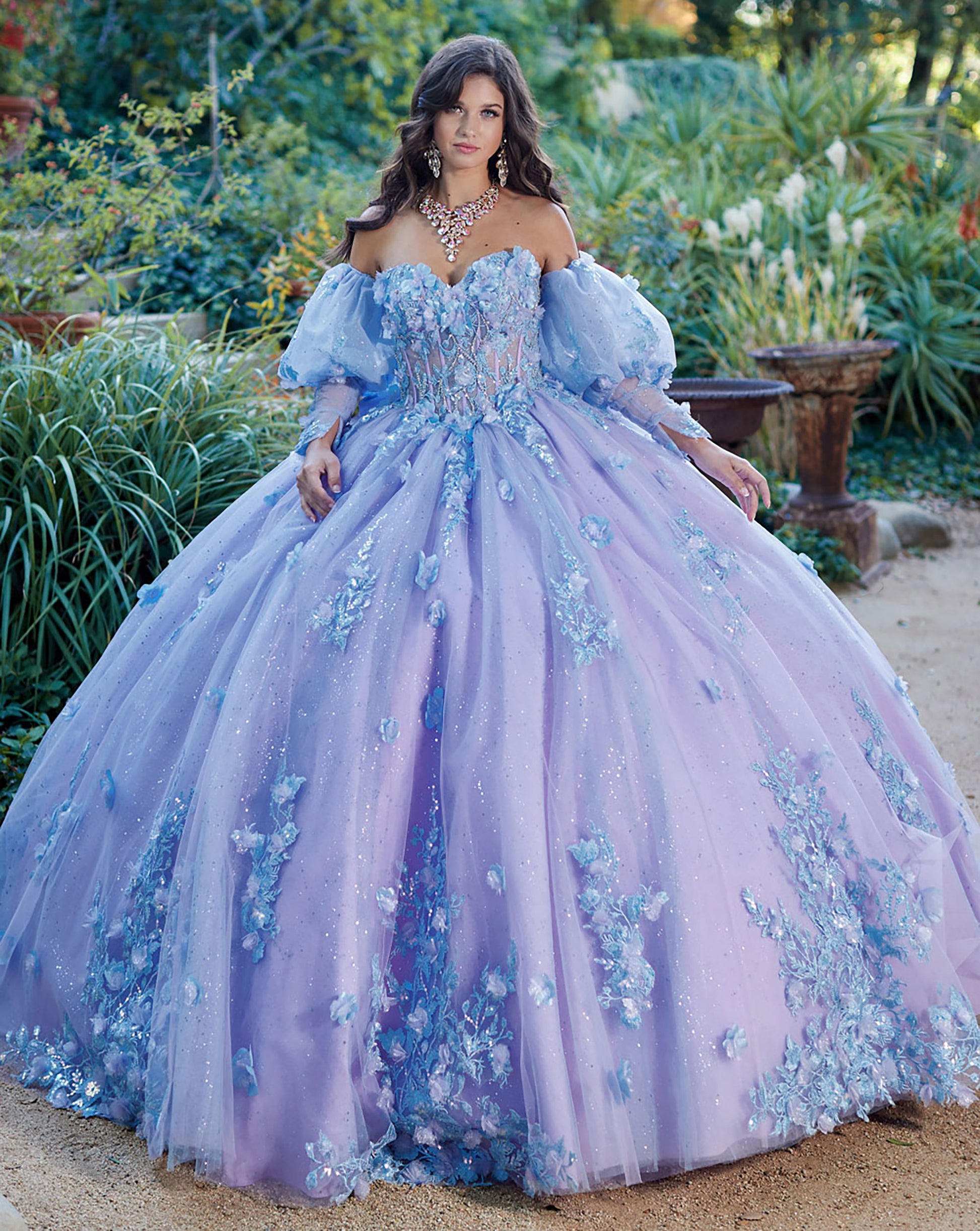 Quinceanera | Detachable Puff Sleeves and Cape Sparkly Ball Gown | Lilac Two Tone 3D Floral Detail Quince Dress - front view of woman wearing dress looking into the camera