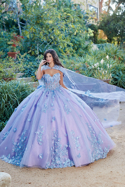 Quinceanera | Detachable Puff Sleeves and Cape Sparkly Ball Gown | Lilac Two Tone 3D Floral Detail Quince Dress - front view of woman wearing dress with one hand near her chin looking into the camera