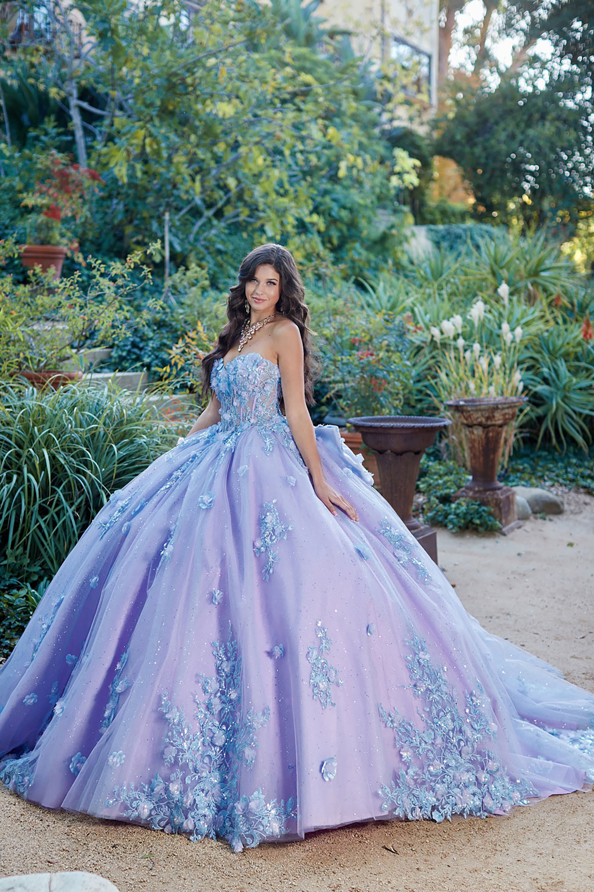 Quinceanera | Detachable Puff Sleeves and Cape Sparkly Ball Gown | Lilac Two Tone 3D Floral Detail Quince Dress - front view of woman wearing dress with body slightly turned to the side