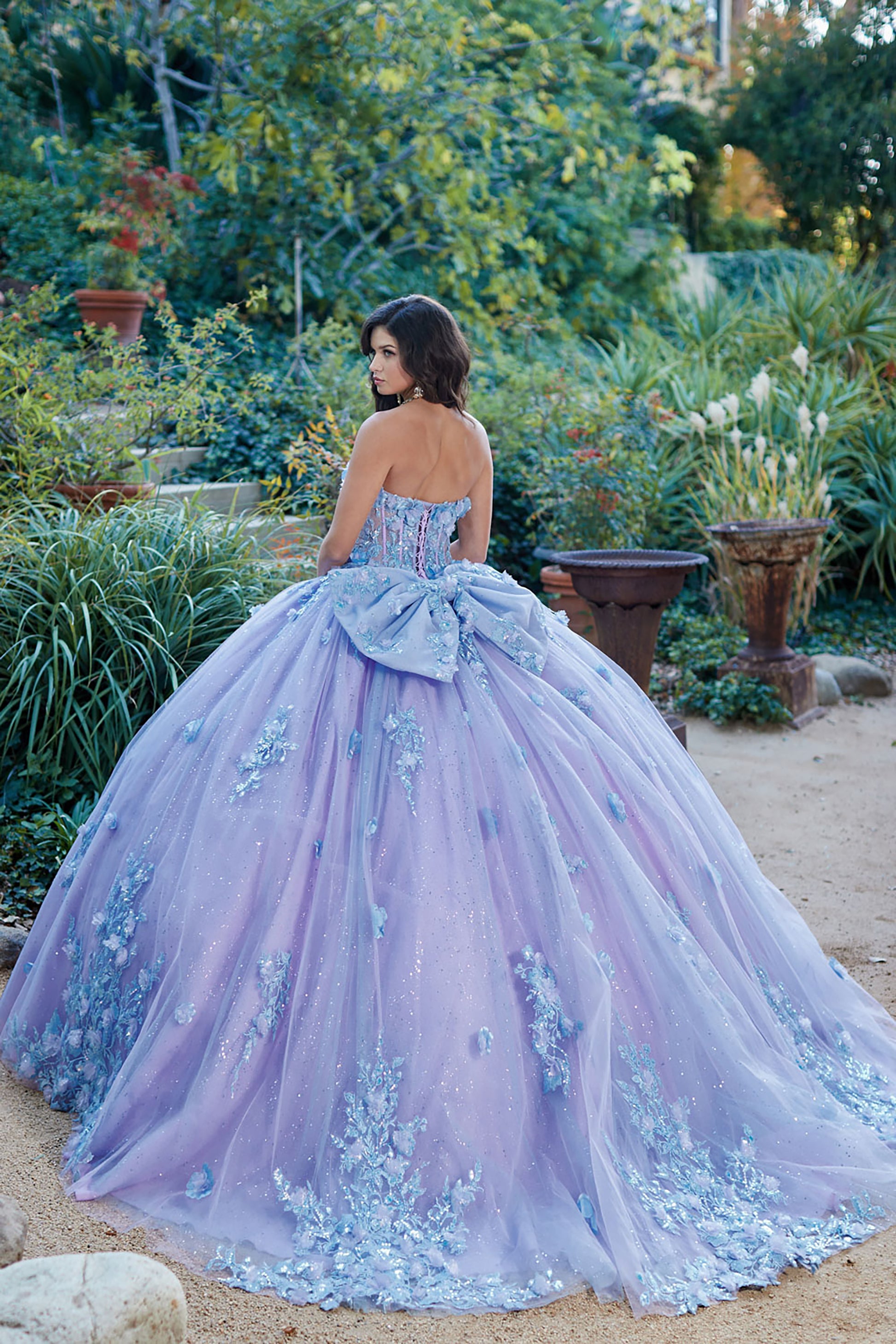 Quinceanera | Detachable Puff Sleeves and Cape Sparkly Ball Gown | Lilac Two Tone 3D Floral Detail Quince Dress - back view of woman wearing dress looking off into the distance