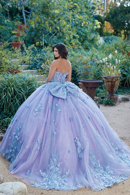 Quinceanera | Detachable Puff Sleeves and Cape Sparkly Ball Gown | Lilac Two Tone 3D Floral Detail Quince Dress - back view of woman wearing dress looking off into the distance