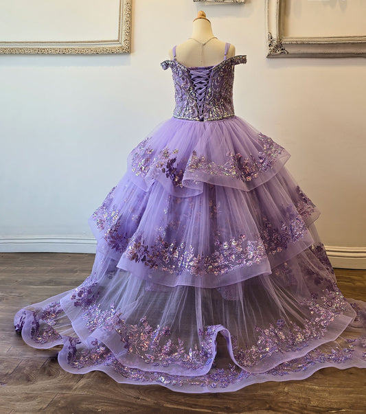 Purple ball gown with floral embellishments on a mannequin against a neutral wall.