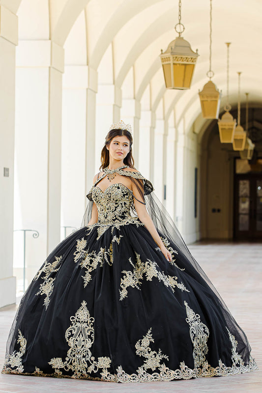 Quinceanera | Black with Gold Embroidered Lace with Stunning Cape Quince Ballgown dress - front view of woman wearing dress and staring of into the distance