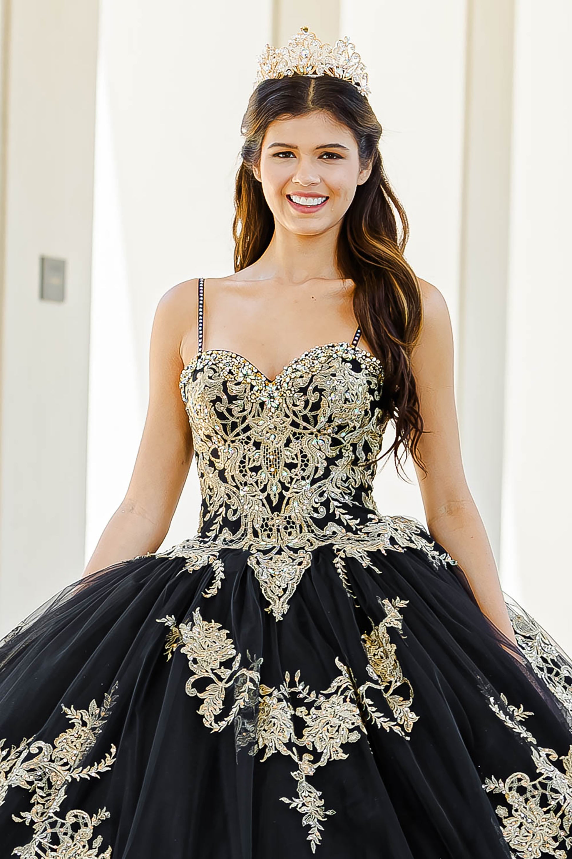 Quinceanera | Black with Gold Embroidered Lace with Stunning Cape Quince Ballgown dress - zoomed in front view of woman wearing dress and crown smiling