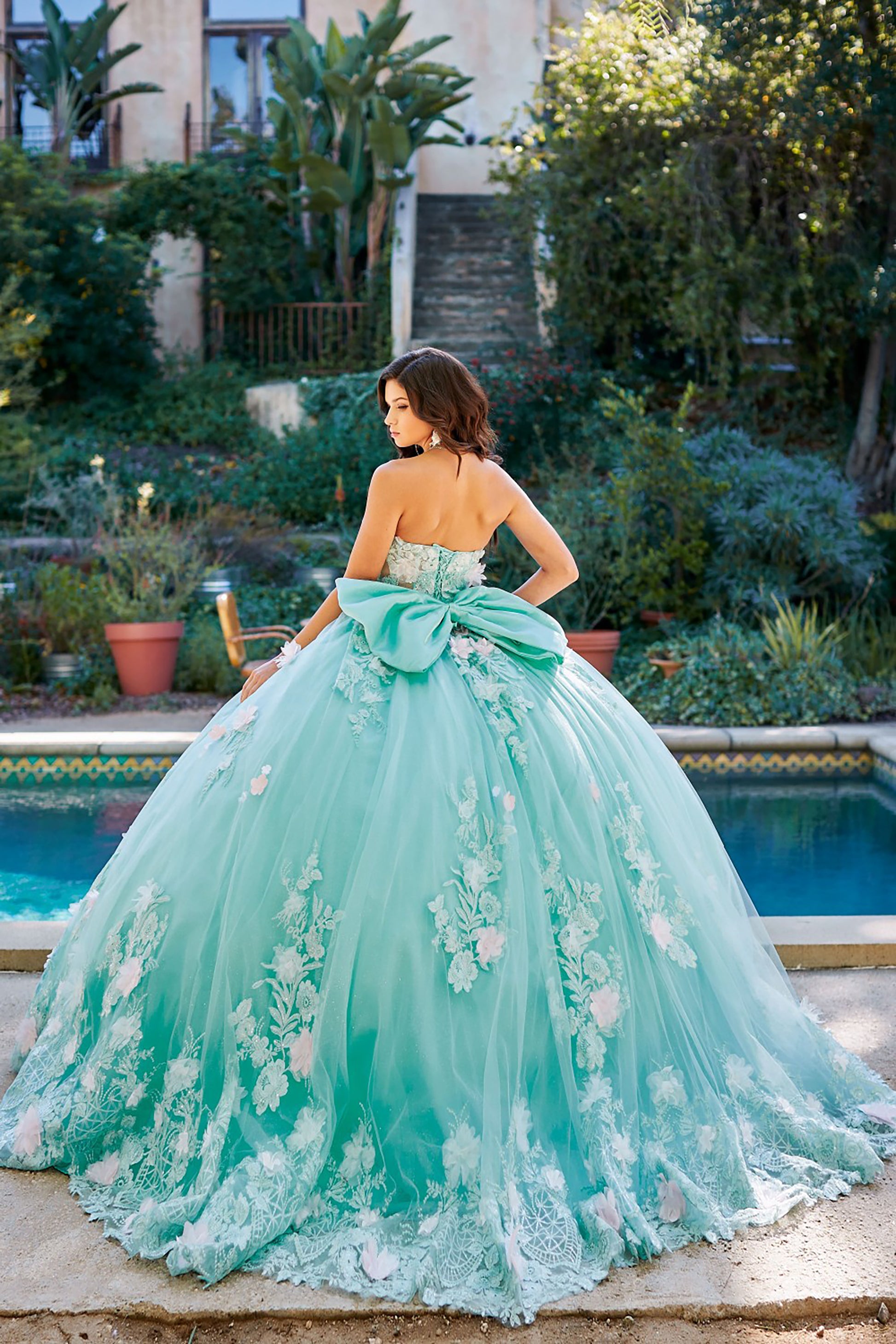 Quinceanera | Mint See-through 3D Flowers, Embroidery, Bead bodice and Glitter Tulle Ballgown w/ detachable Big Bow - back view of woman wearing dress