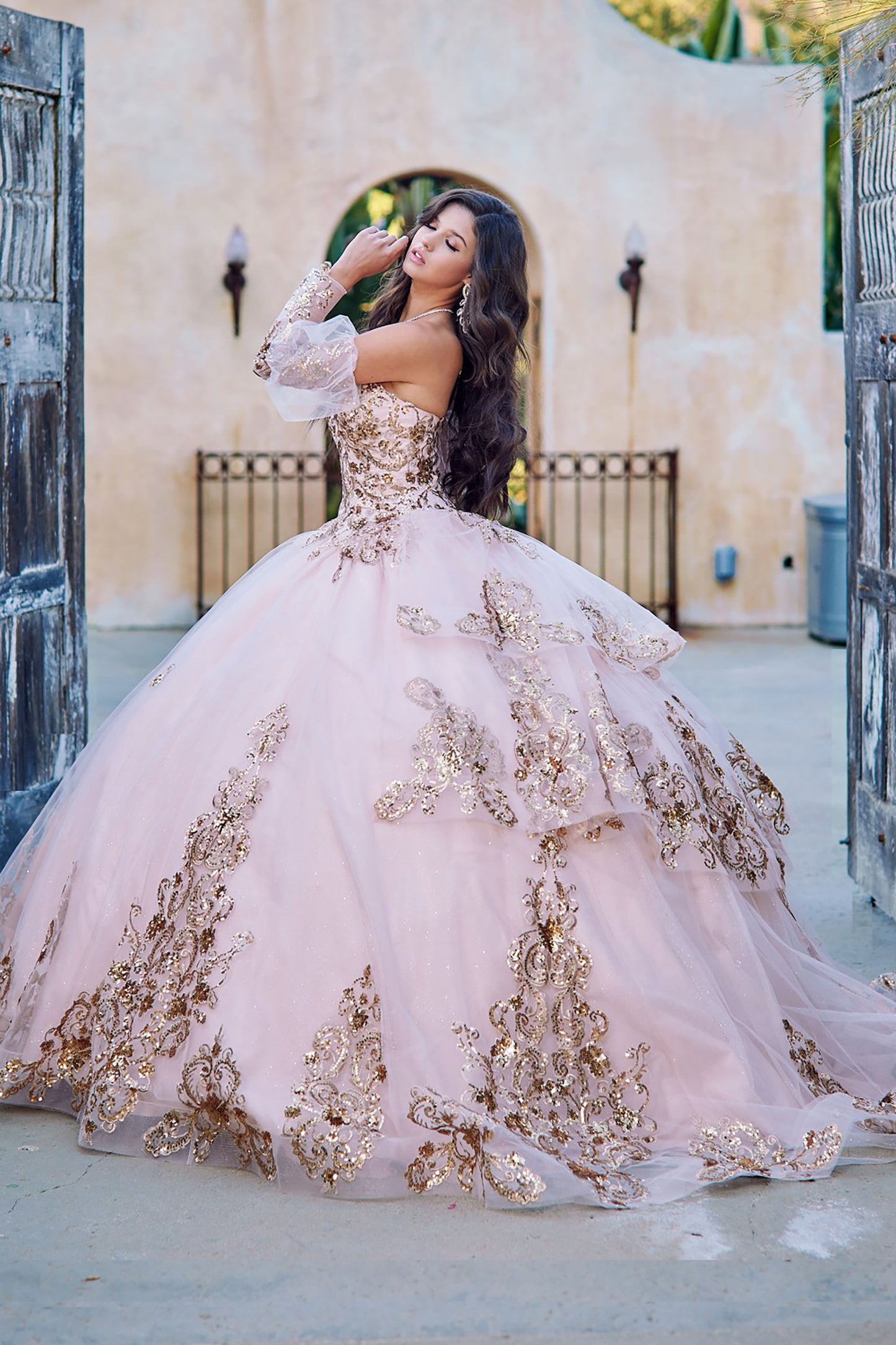 Quinceanera | Detachable Puffy Sleeve Champagne Ballgown | Gold Embroidered and Sequin Bodice Quince dress - side view of woman wearing dress with one hand up near face