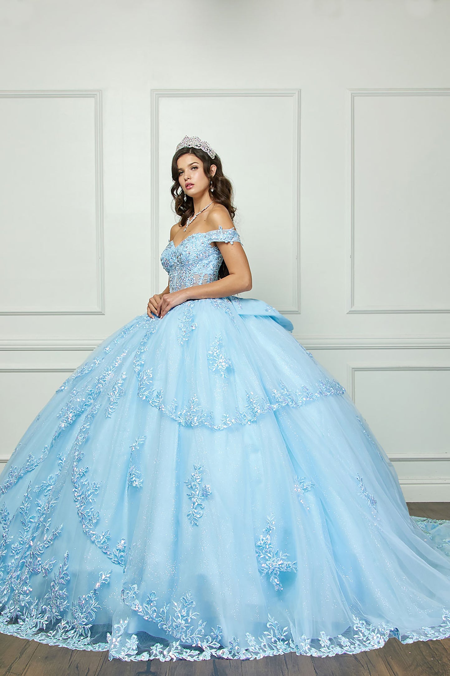 Quinceanera | Cinderella Blue Sparkling Rhinestones Bodice Multi-tiered Illusion Skirt Embroidery Off Shoulder Quince dress - front/side view of woman wearing dress and crown