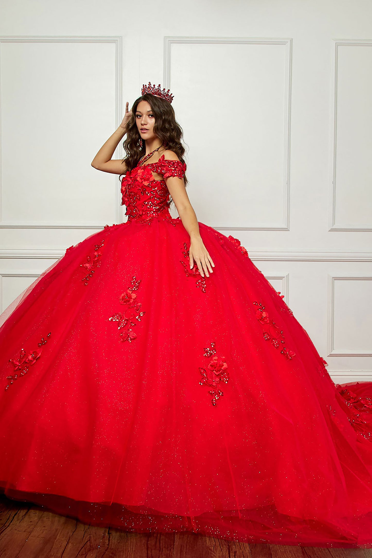 Red Long Train Off-Shoulder Sequin detail 3D Flower and Butterflies bodice with Sparkle Tulle Quince Dress - side view of woman wearing dress with red crown on her head brushing her hair aside