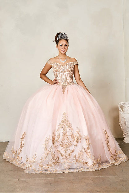 Woman in a pink and gold embroidered gown with a tiara, standing against a plain background.