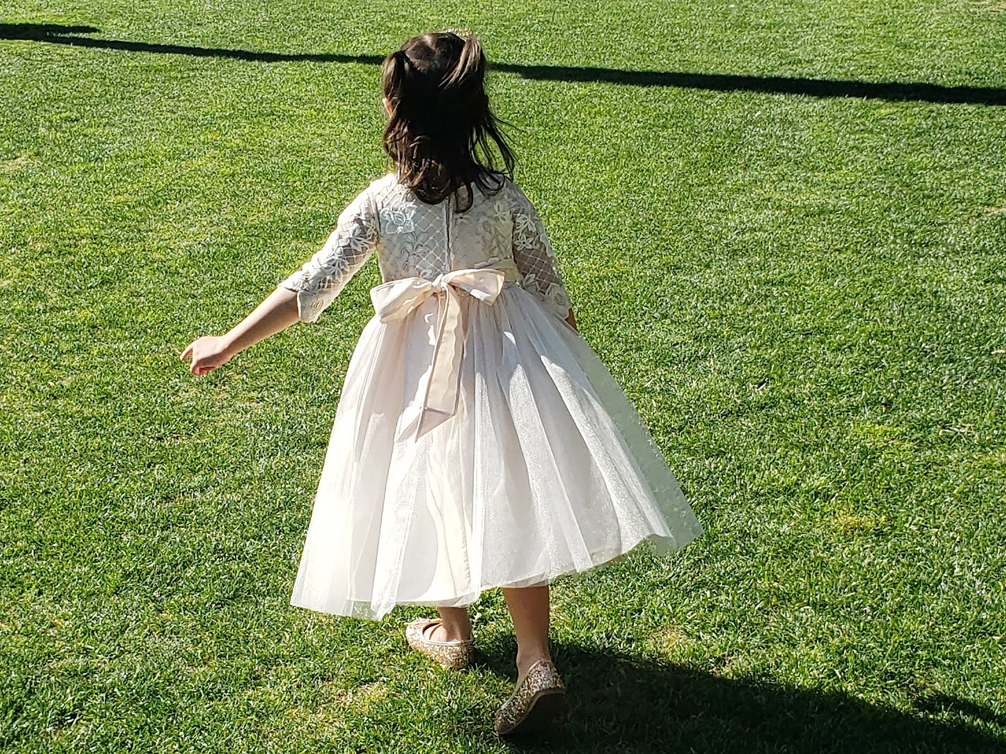 Champagne USA Made | 3/4 sleeve Lattice Flower Embroidered Lace with Satin & Crystal Tulle Flower Girl Dress - back view of girl wearing dress running with bow on back