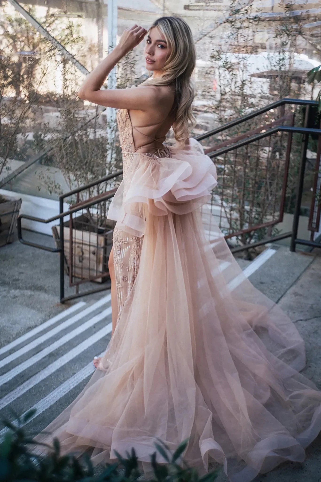 Back full-length view of of a  Gold jewel-embellished mermaid prom dress with side slit and detachable mesh layer