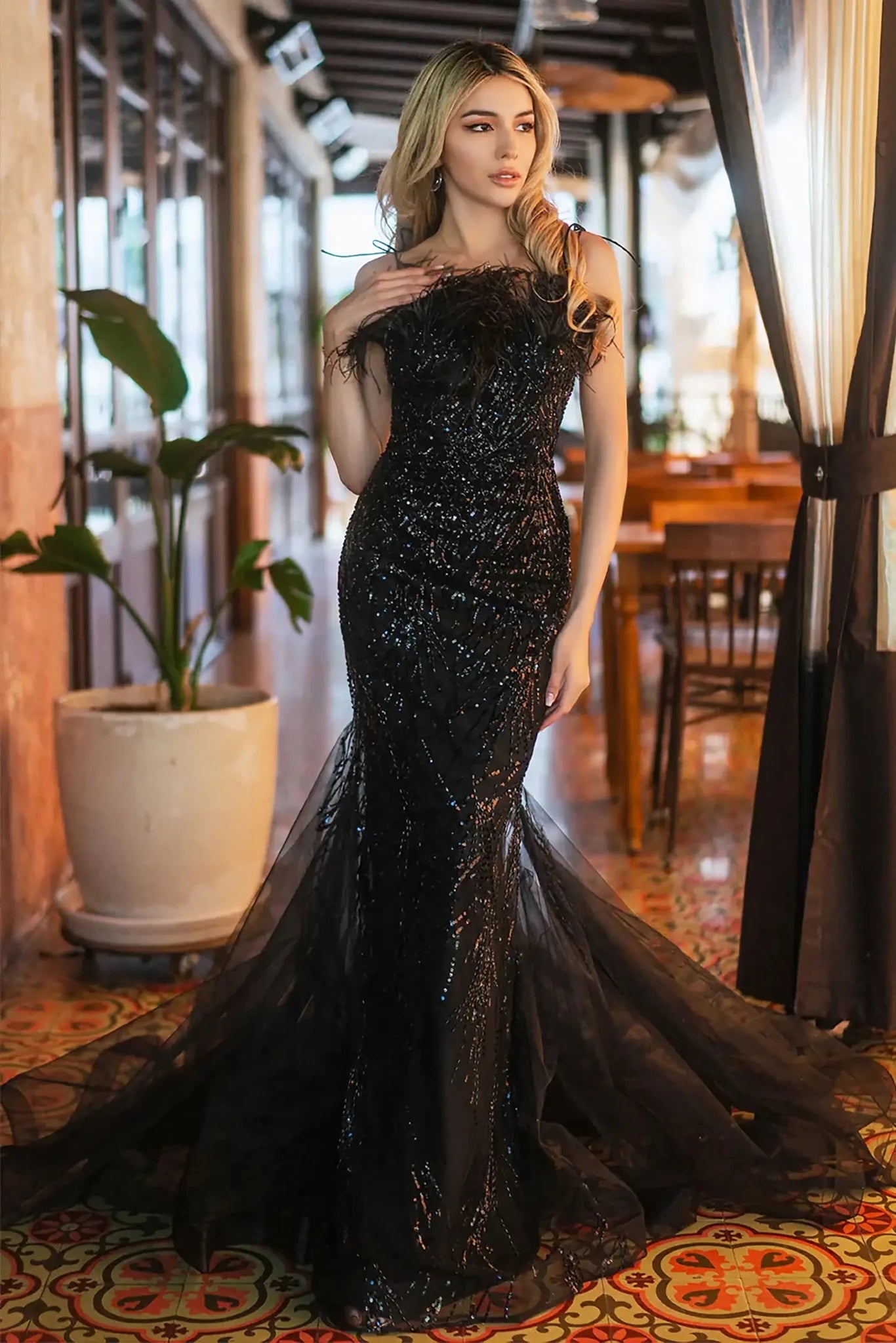 Front full-length view of a  Black sequin sweetheart trumpet prom dress with feather embellishments
