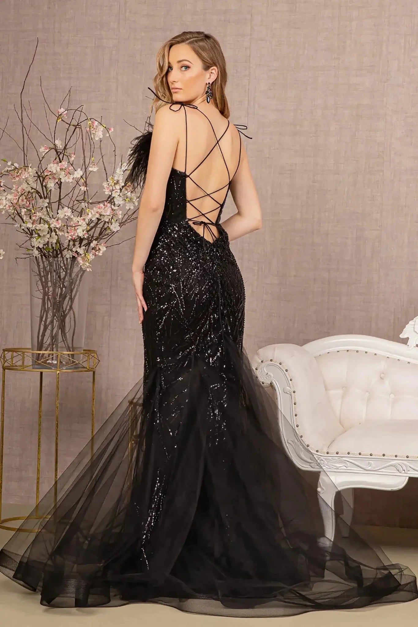 Back full-length view of of a  Black sequin sweetheart trumpet prom dress with feather embellishments