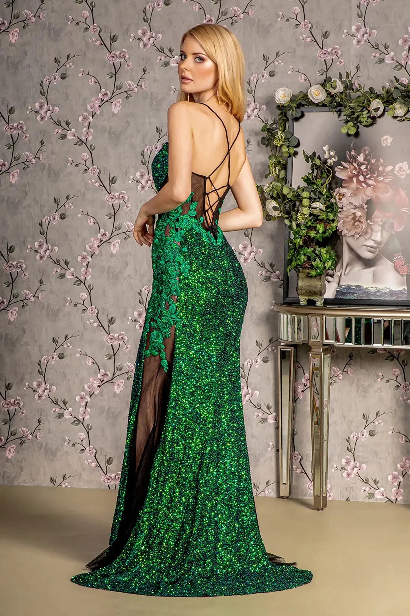 Back full-length view of of a  Green & black mermaid prom dress with sheer bodice and floral embroidery