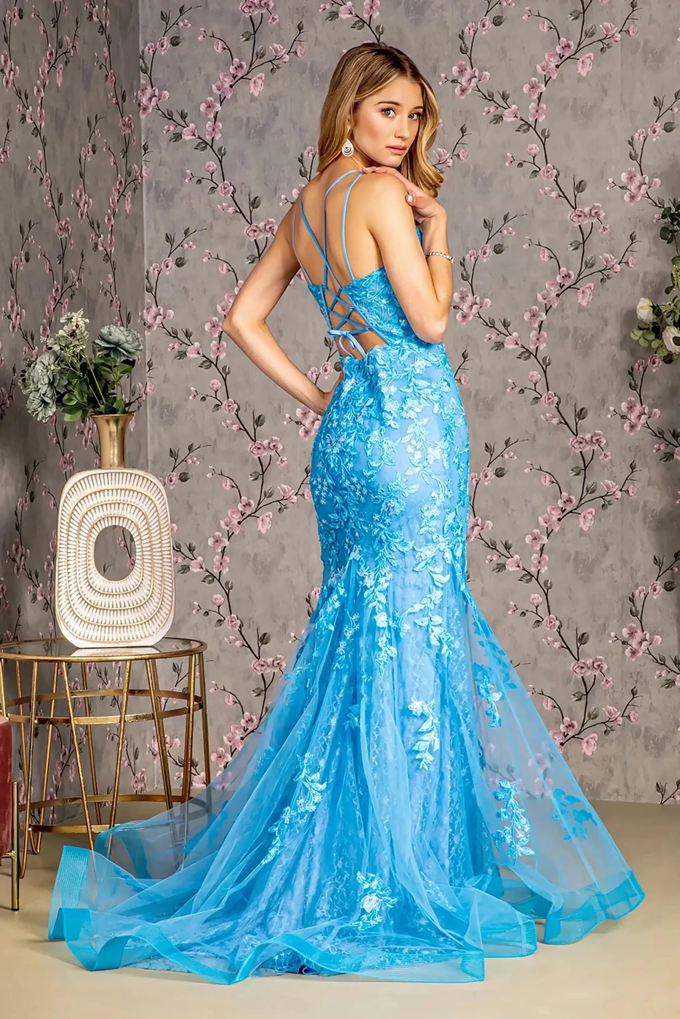 Back full-length view of of a  Ocean blue mermaid prom dress with sheer bodice and floral sequin embroidery