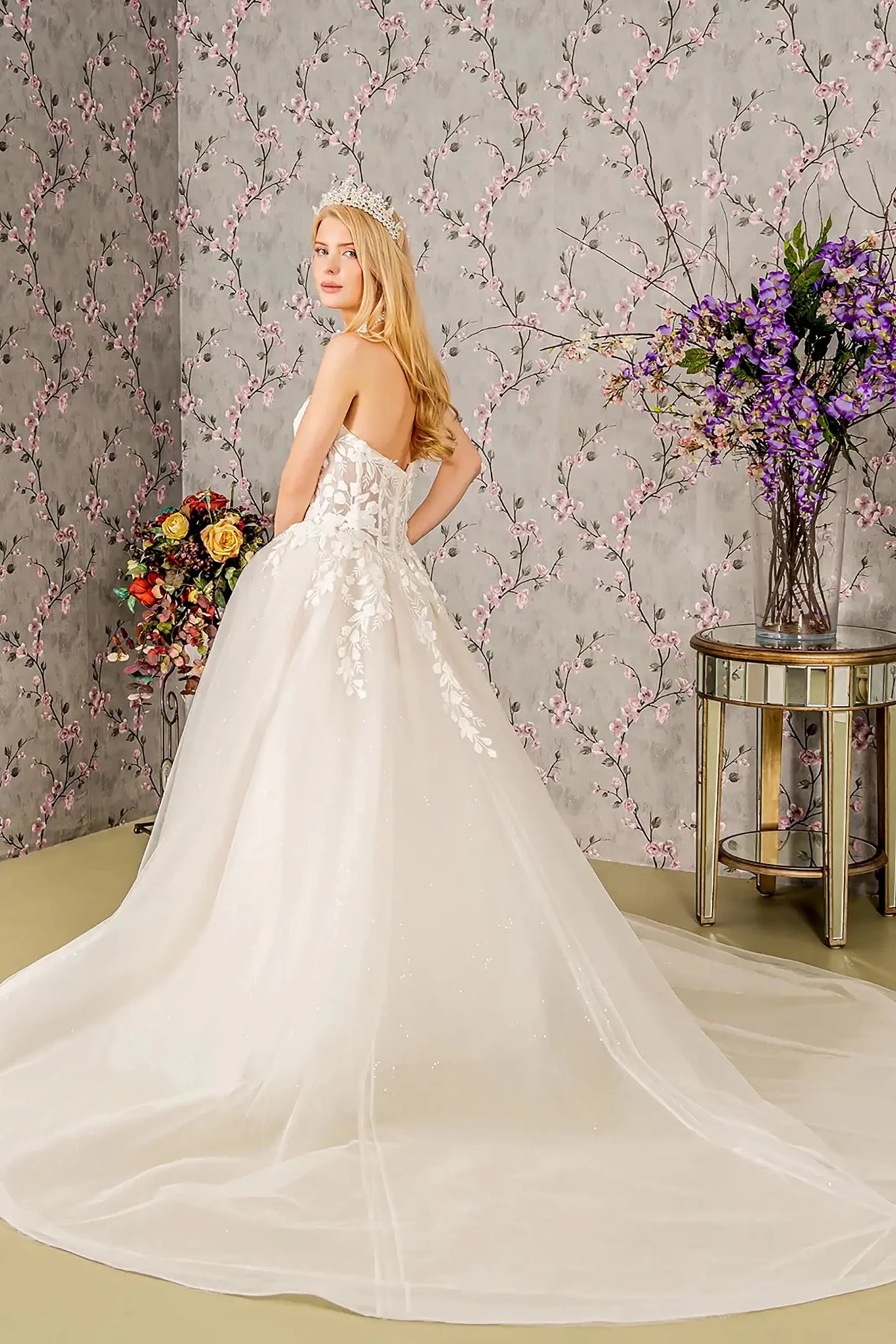 Back full-length view showcasing the classic ball gown silhouette and the expansive, floor-sweeping train adorned with cascading floral lace and sparkling sequin details.