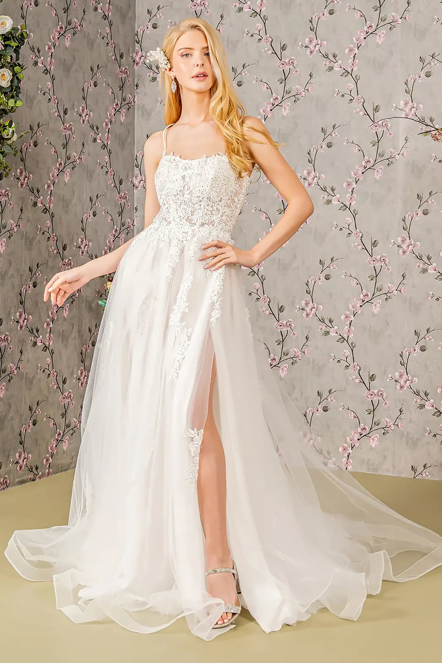 Front full-length view of an ivory A-line wedding dress featuring a clean straight-across neckline, delicate beaded spaghetti straps, and a voluminous layered skirt.