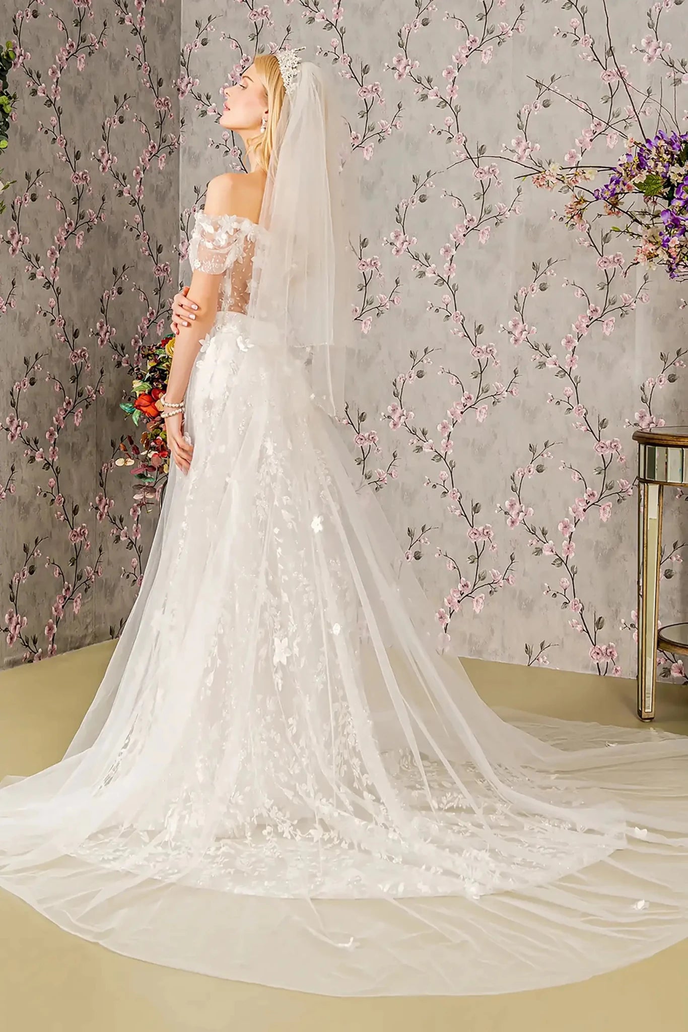 Back full-length view showcasing the dramatic sweep of the long flowing mesh cape as it extends from the shoulders to trail gracefully behind the A-line skirt.