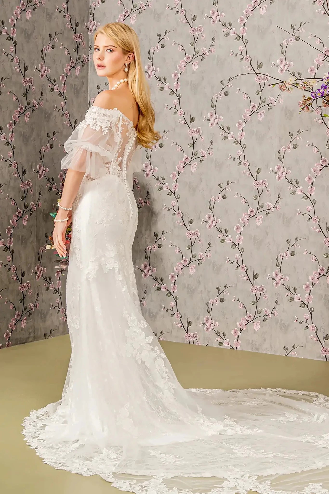 Back full-length view of Ivory mermaid wedding dress with sweetheart neckline, short sheer sleeves, floral embroidered beaded bodice, and sheer back with button closure and zipper