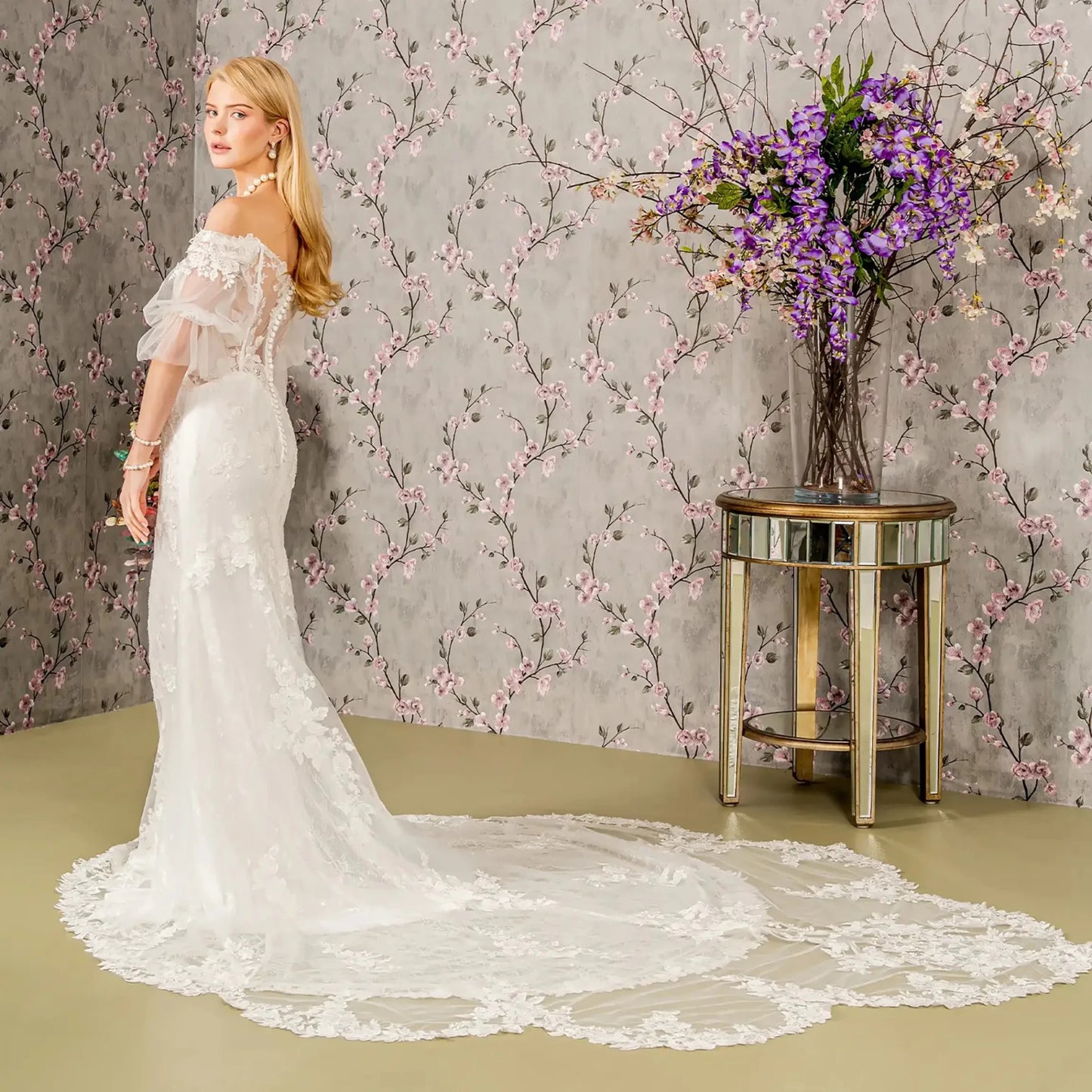 Back full-length view displaying the contoured fit of the mermaid gown and the way the floral lace motifs extend down toward the flared hem and bridal train.