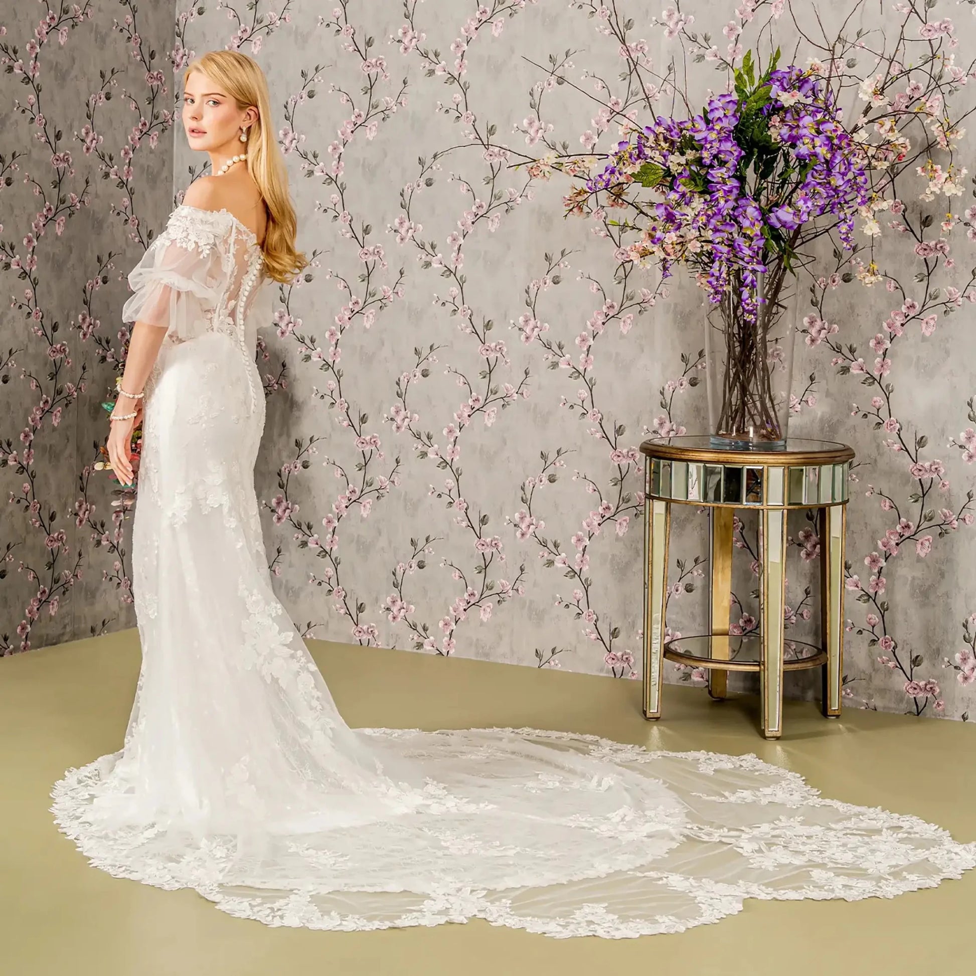 Back full-length view displaying the contoured fit of the mermaid gown and the way the floral lace motifs extend down toward the flared hem and bridal train.