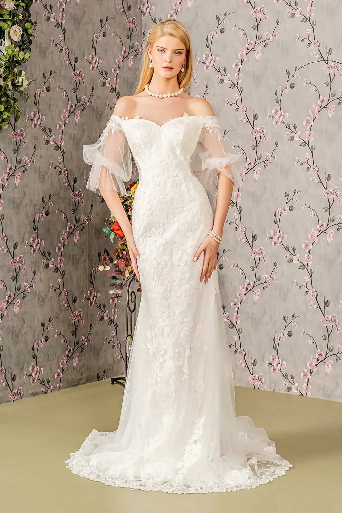Front full-length view of an ivory mermaid wedding dress featuring a sweetheart neckline, short sheer sleeves, and a fitted silhouette that flares into a graceful train.