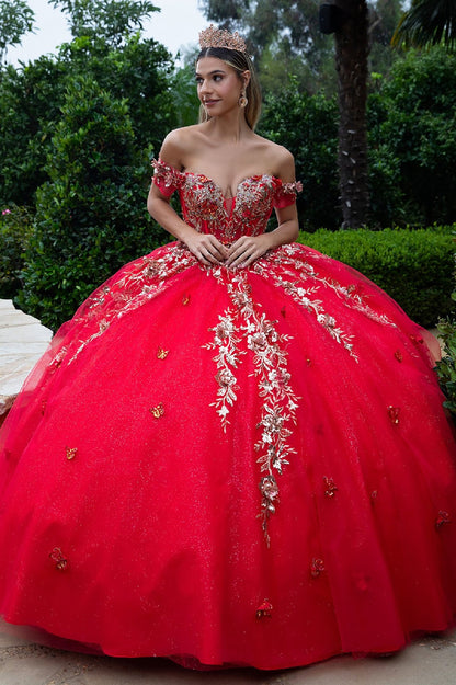 Front view of quinceañera red gown with gold embellishments and long train worn outdoors on stone pathway