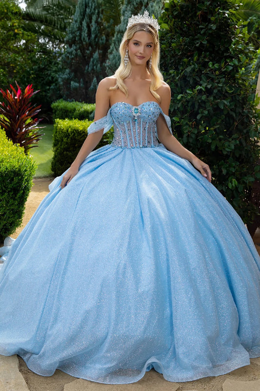 Woman in a light blue quince ball gown with off and a tiara, standing outdoors.