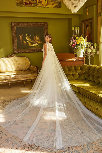 Back full-length view of Off White trumpet wedding dress with V-neck corset bodice, spaghetti straps, beaded embroidery, sequins, floral lace underlayer, zipper back, and matching cape train