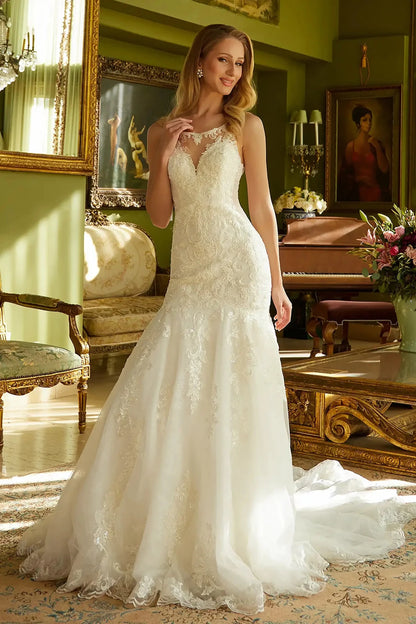 Front full-length view of an off-white mermaid wedding dress featuring an illusion V-neckline, a sleeveless embroidered bodice, and a fitted skirt that flows into a flared train.