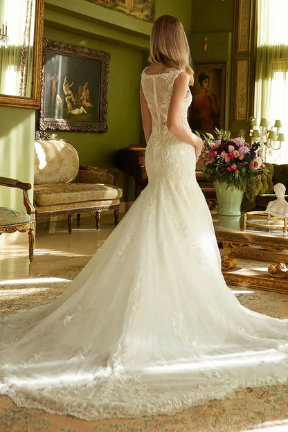 Back full-length view displaying the dramatic extension of the flared train and the detailed lace patterns that decorate the rear profile of the gown.
