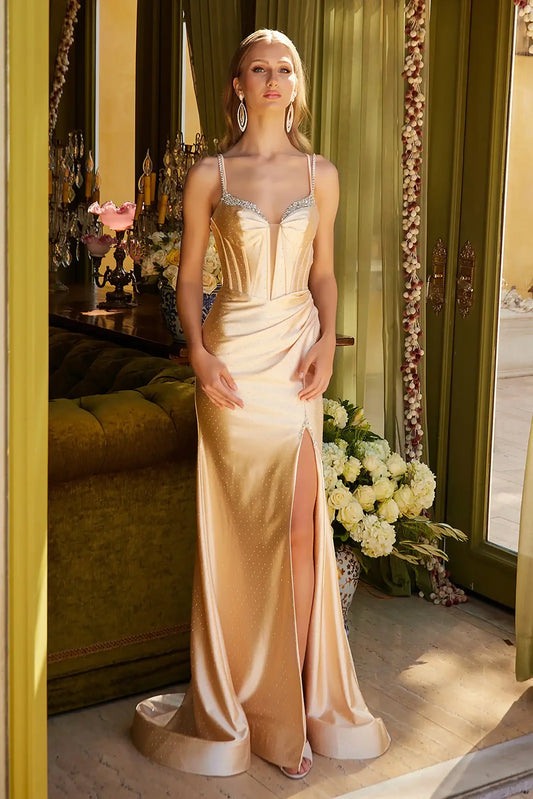 Front full-length view of a champagne fitted prom dress with a beaded sweetheart corset bodice, double spaghetti straps, satin skirt, side ruching, lace-up back, and front slit.