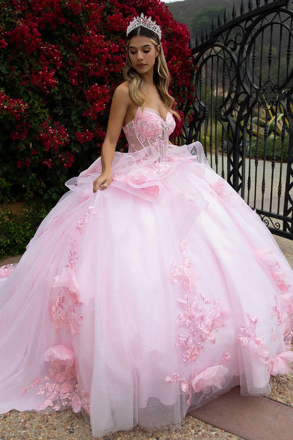 Woman in a pink floral dress with 3D big sheer flower and embroidery on the ruffled skirt standing outdoors with a decorative background