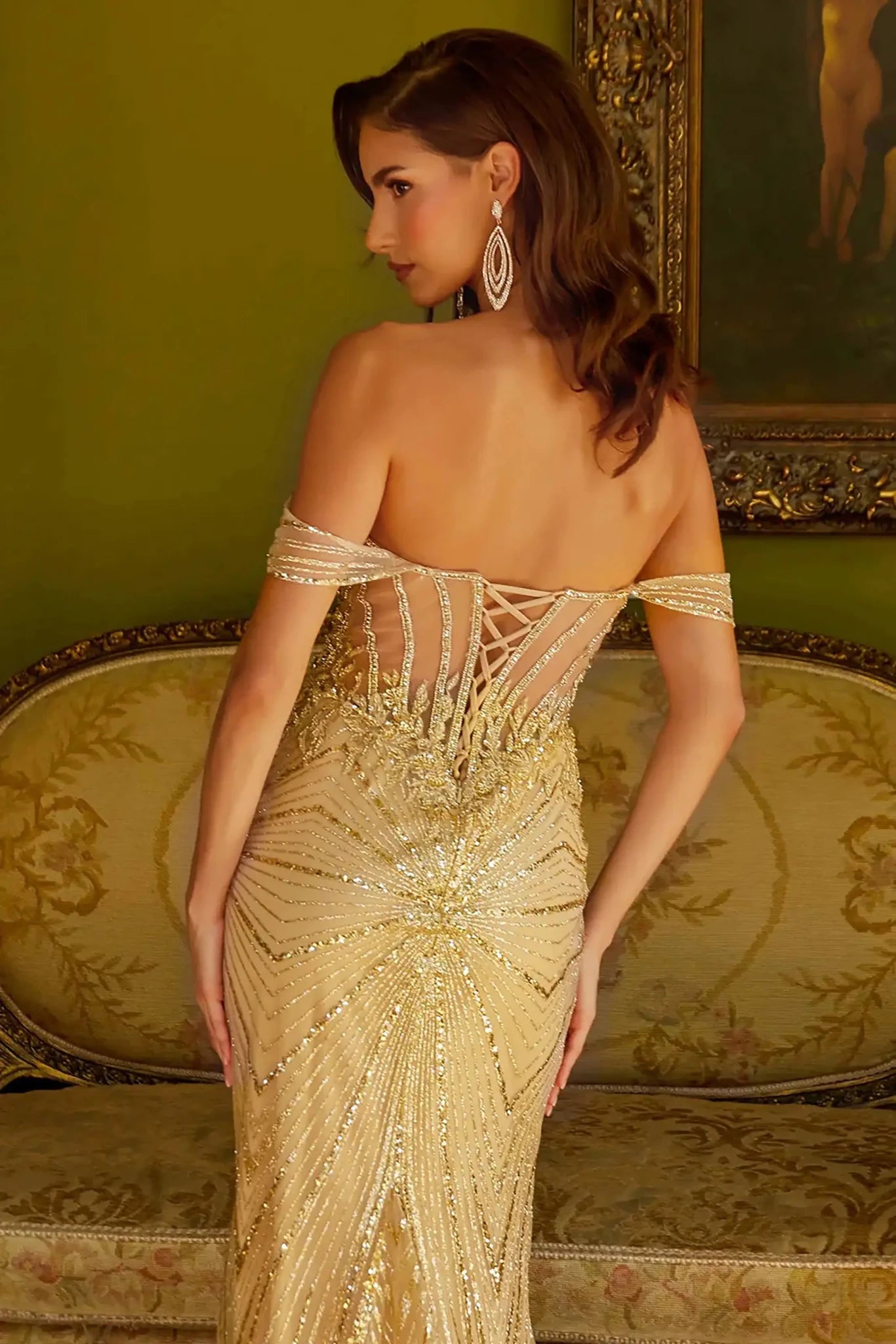Back close-up upper view of a champagne fitted prom dress with a beaded sweetheart corset bodice, off-shoulder straps, sheer mesh sides, and a floor-length silhouette.