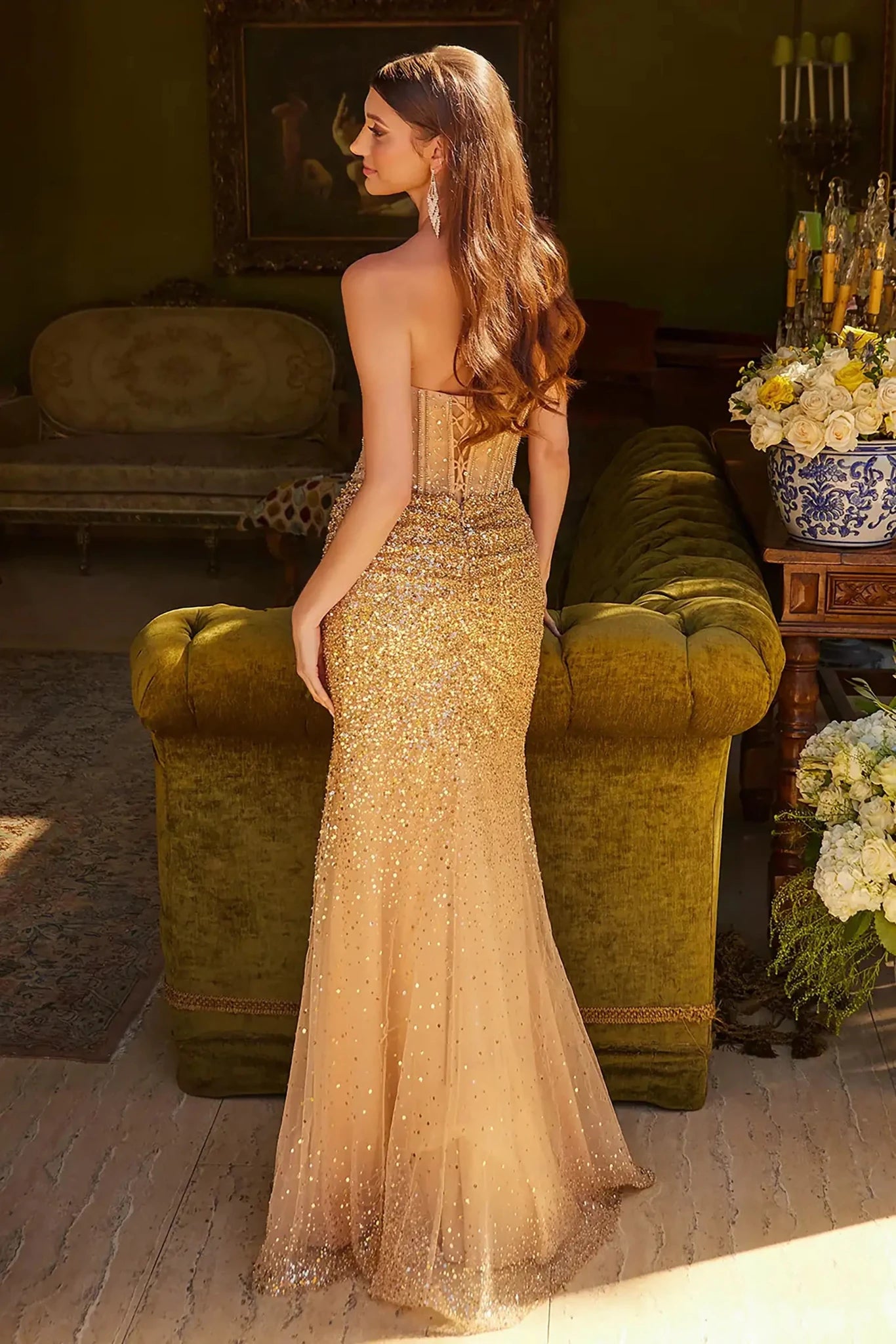 Back full-length view of of a  Gold strapless beaded prom dress with v-neck corset and front slit