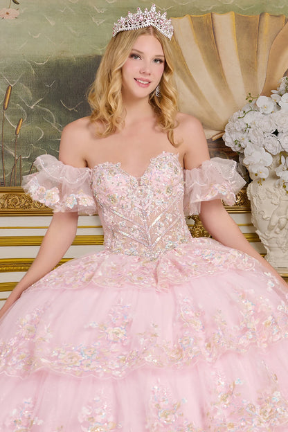Woman in a pink quince gown with floral details and a tiara, sitting on an ornate chair.