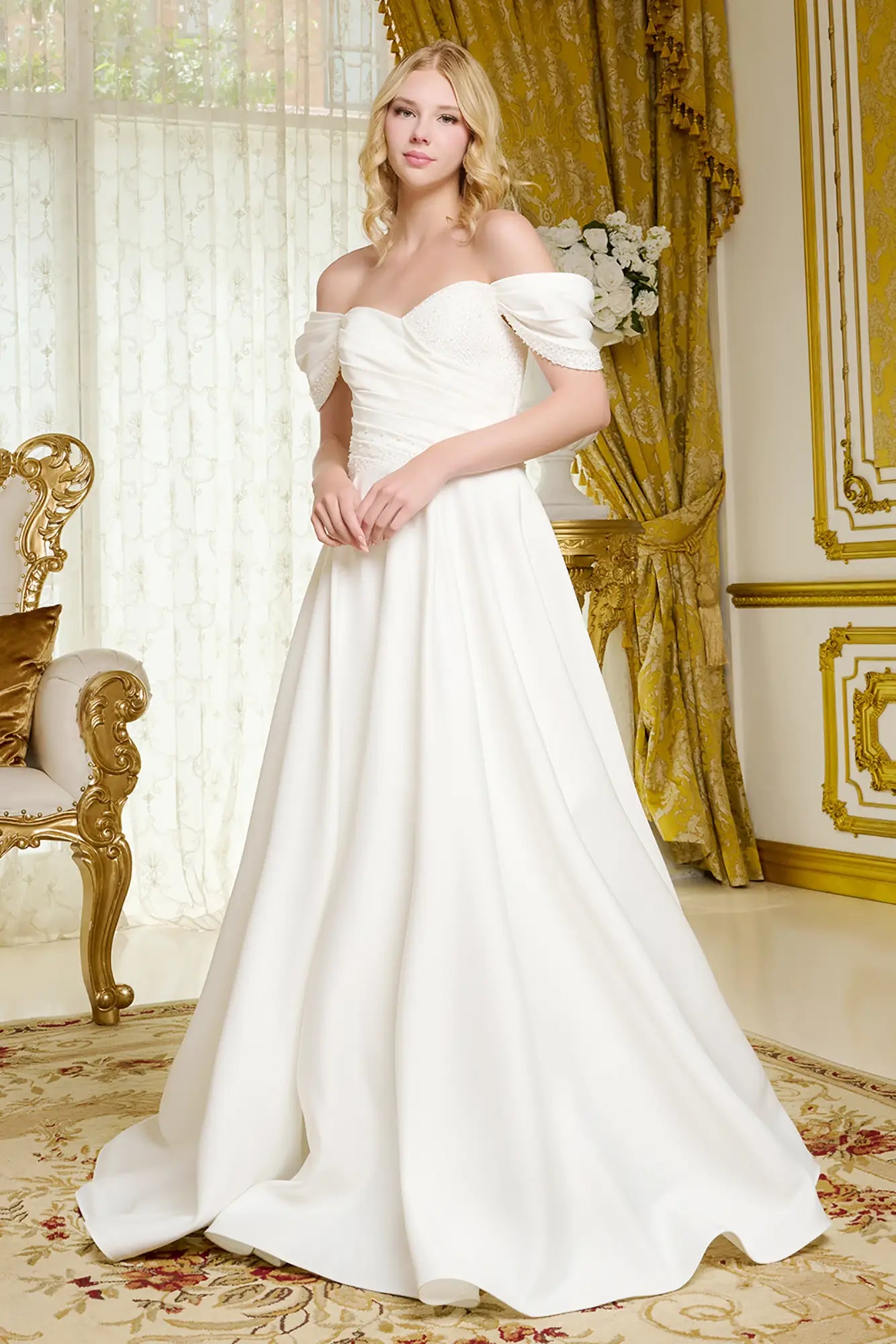 Woman in a white wedding dress standing in an elegant room with gold accents.