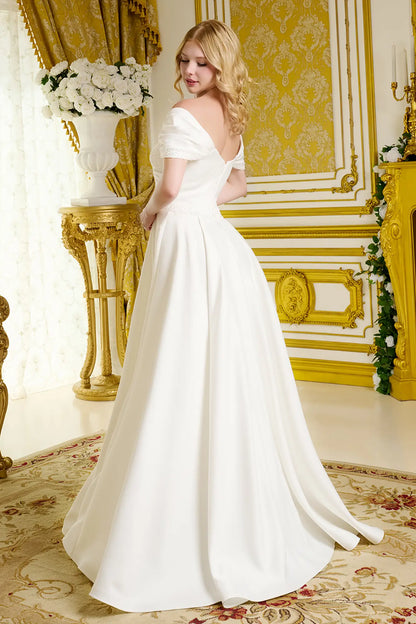 Woman in a white wedding dress standing in an ornate room with gold accents.
