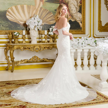 Woman in a white wedding dress standing in an ornate room with decorative elements.