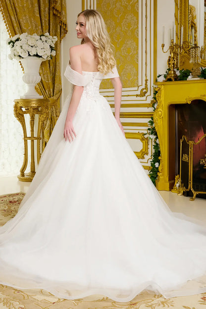 Woman in a white wedding dress standing in an opulent room with gold decor.