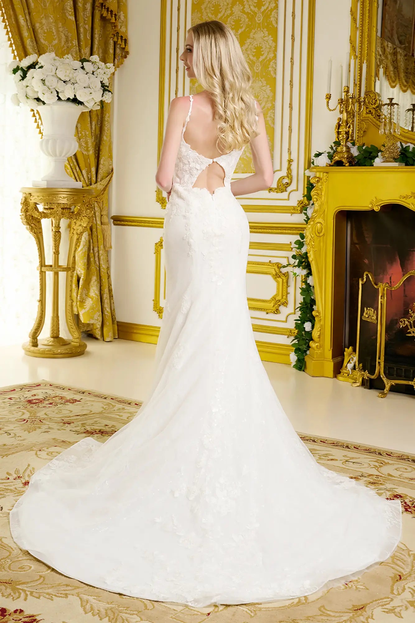 Woman in a white wedding dress standing in an opulent room with gold decor.