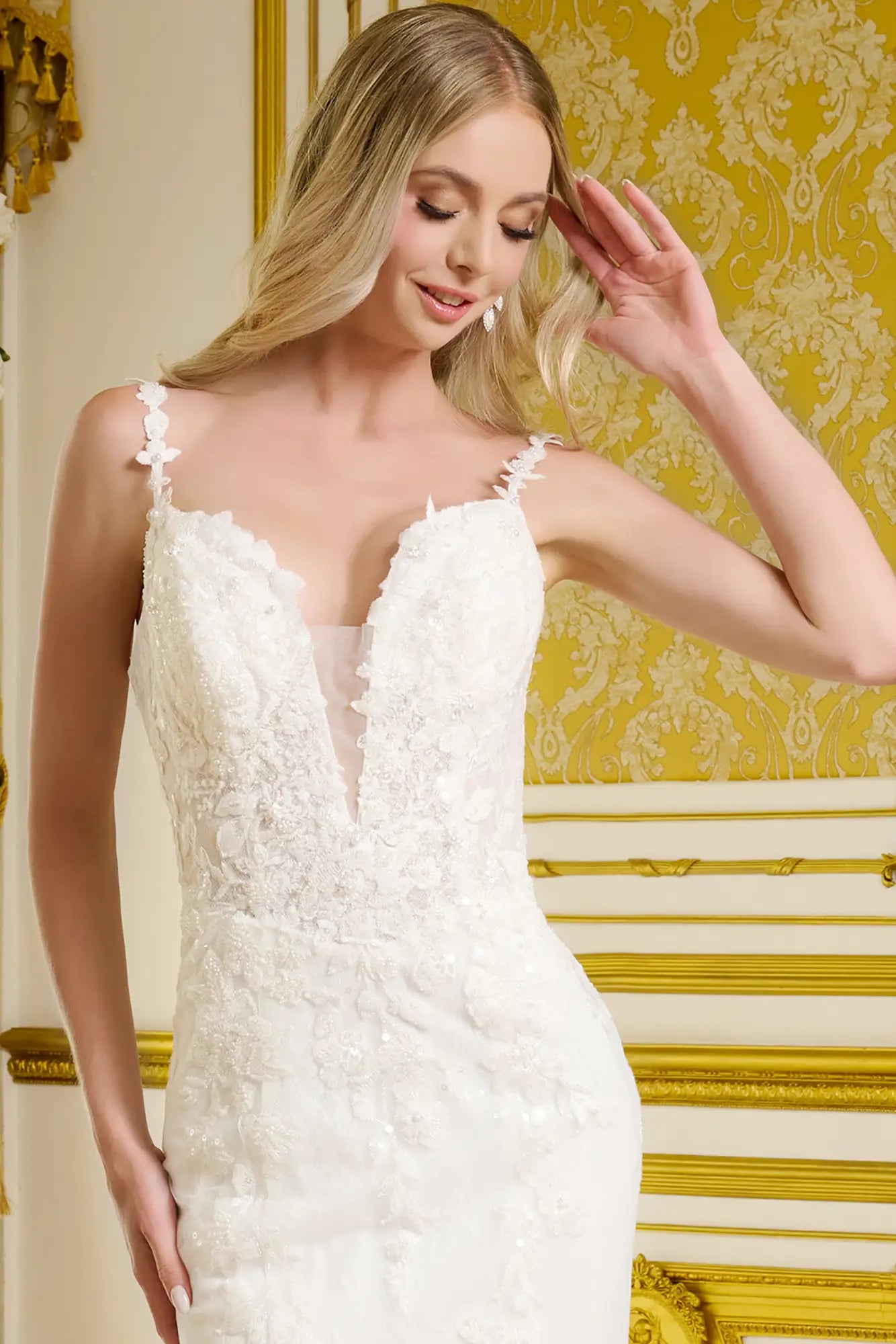 Woman wearing a white lace wedding dress in a decorated room with gold accents.