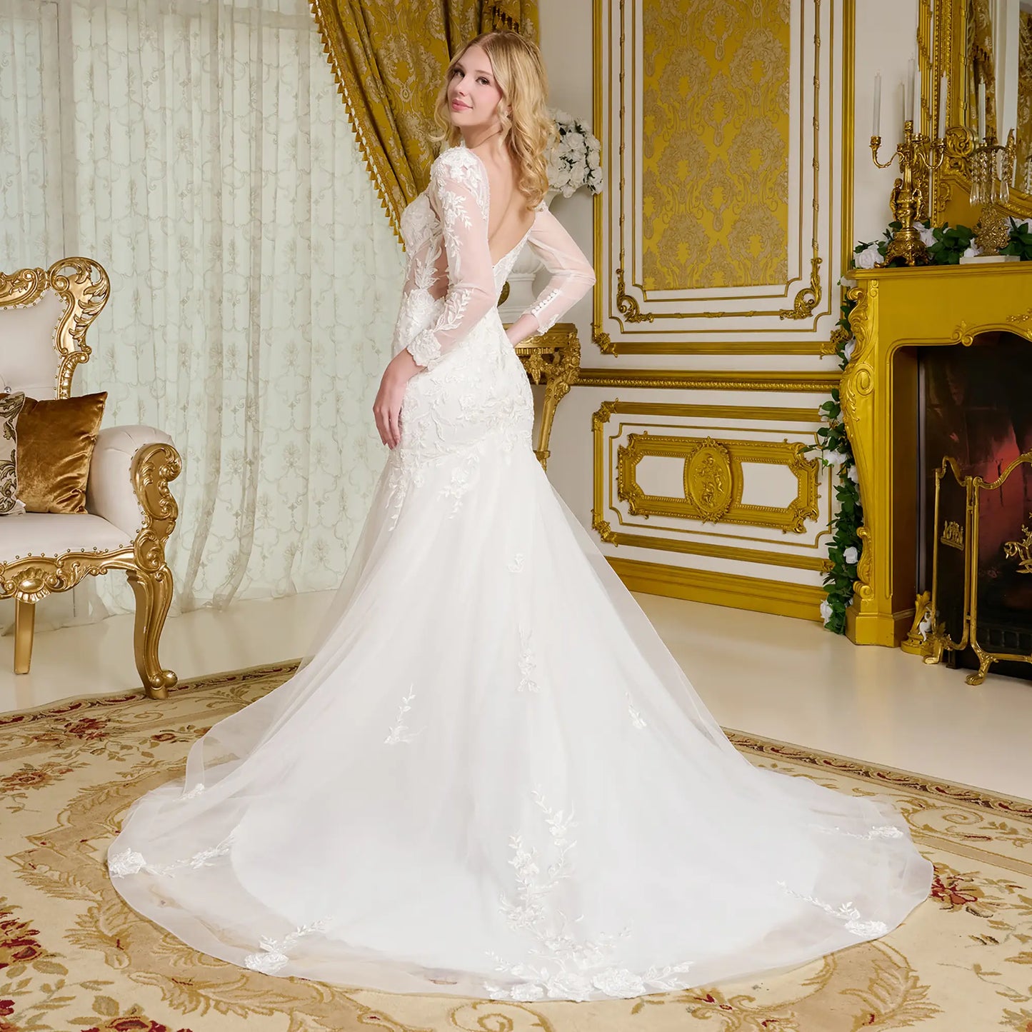 Woman in a white wedding dress standing in an opulent room with gold accents.