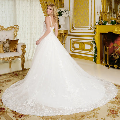 Woman in a white wedding dress standing in an opulent room with gold decor.