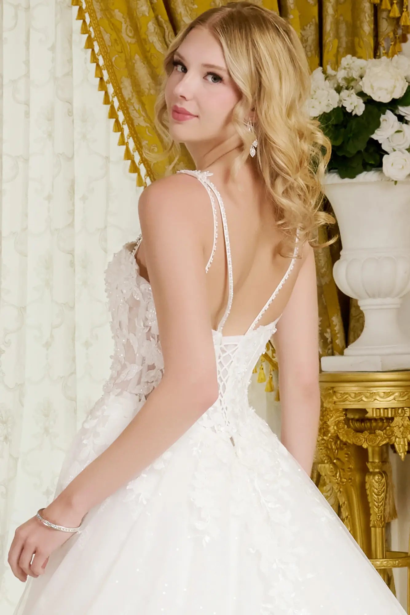 Woman in a white wedding dress with a gold curtain and floral background