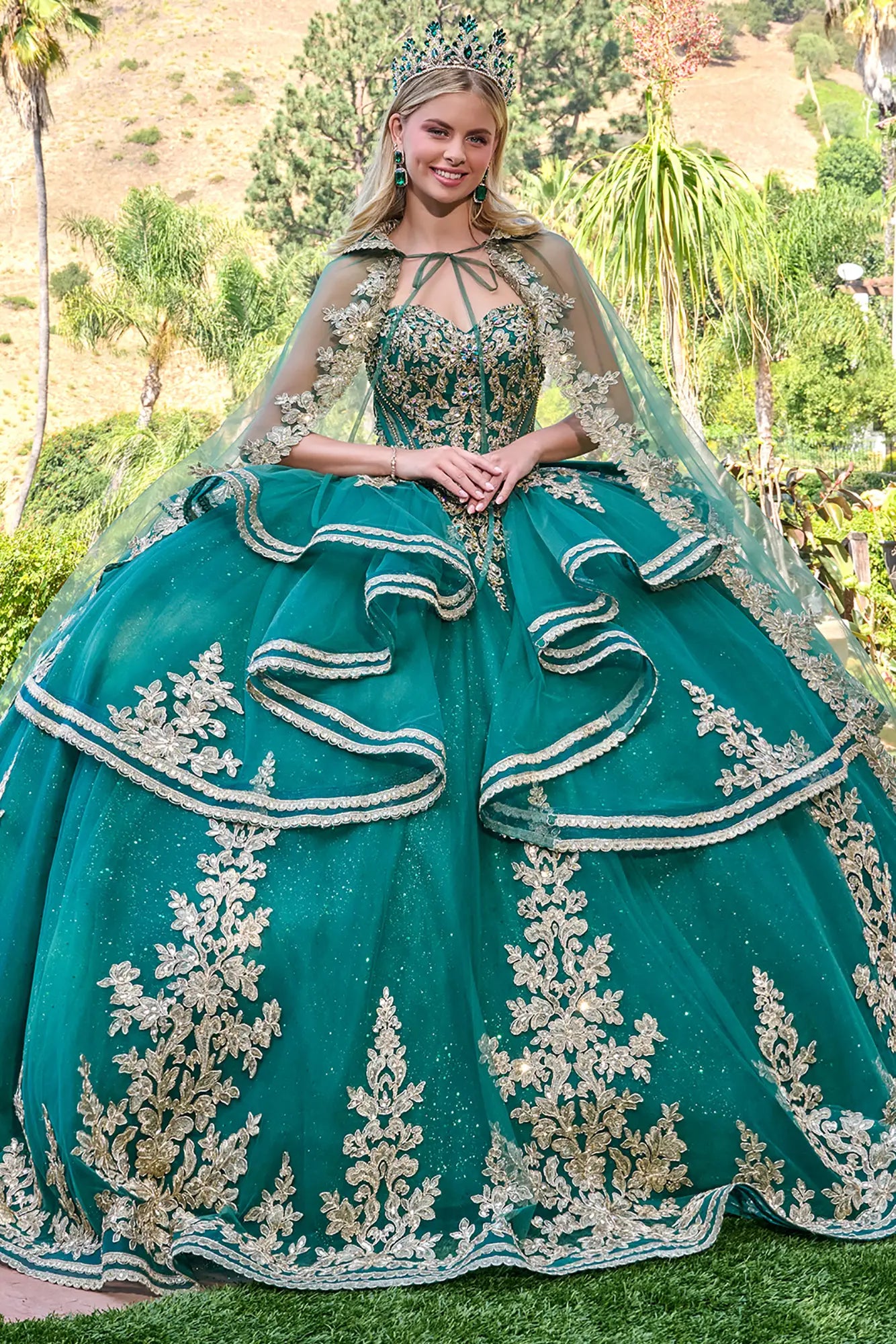 Woman in a green quinceañera dress with a tiara, standing outdoors.