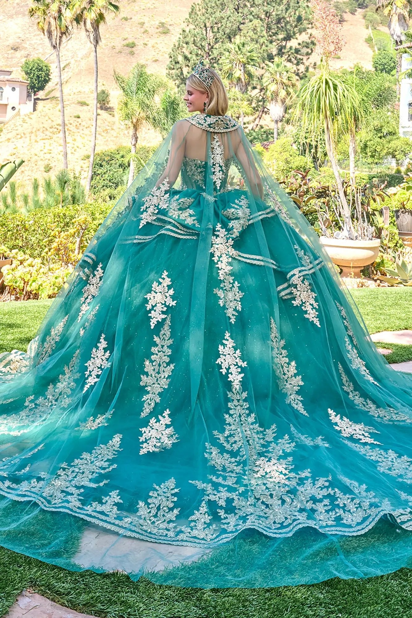 Woman in a green quinceañera dress with gold sequin embroidery standing in a garden.