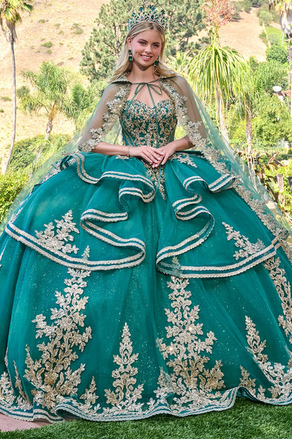 Woman in a green quinceañera dress with a tiara, standing outdoors.