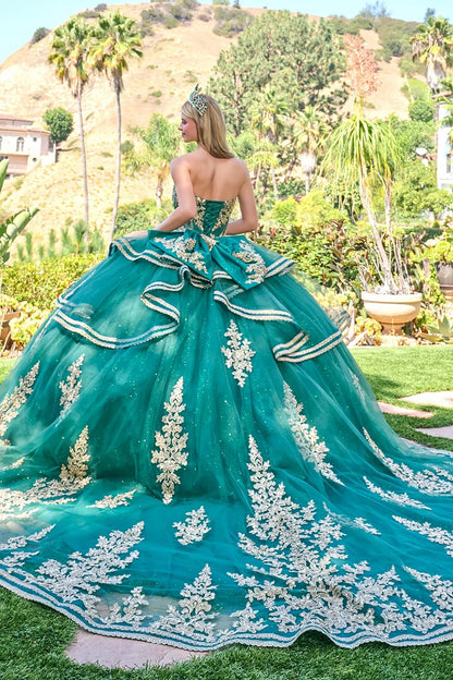Woman in a green quinceañera dress with gold sequin embroidery standing in a garden.